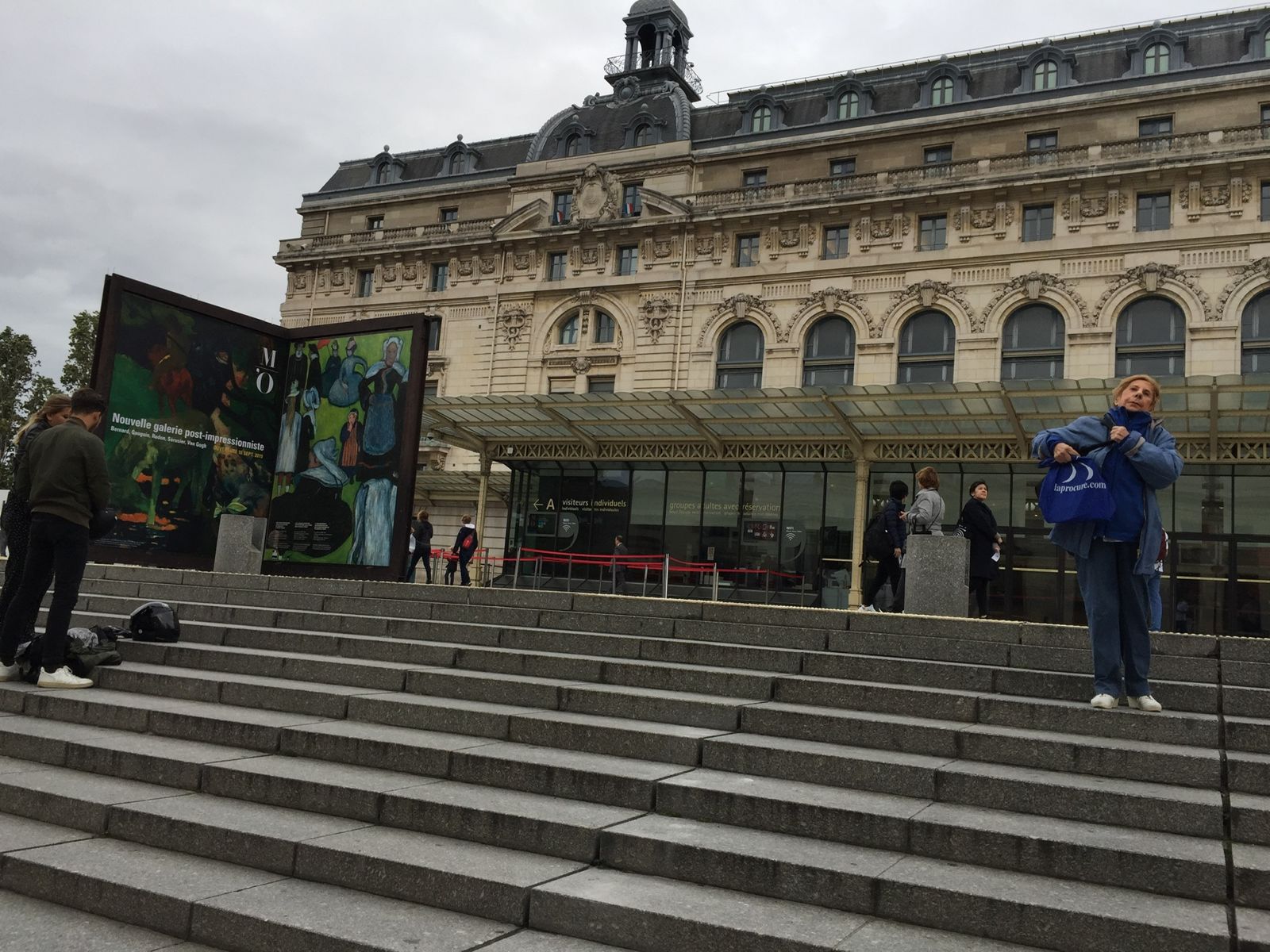 The Musee d'Orsay seen from the steps outside on an overcast day, its clock tower above the arched glass front.