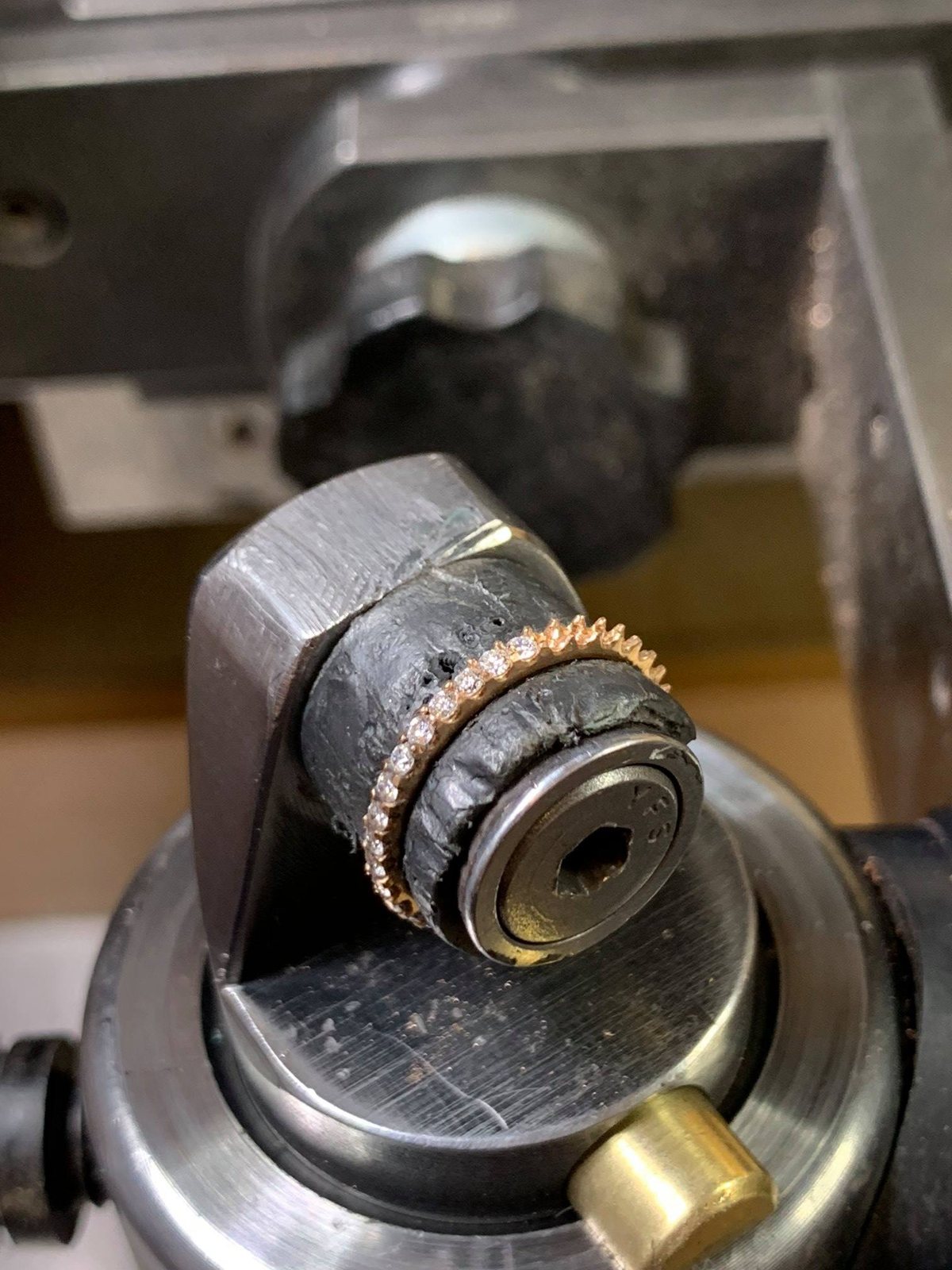A rose gold band held in a tool on Elliot Gaskin's workshop bench.